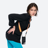 Model wearing the black Bandolier-style leather crossbody phone case, demonstrating its practicality with the adjustable strap comfortably slung over the shoulder.