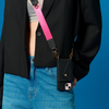 Model wearing the black Bandolier-style leather crossbody phone case, demonstrating its practicality with the adjustable strap comfortably slung over the shoulder