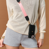 Model wearing the black Bandolier-style leather crossbody phone case, demonstrating its practicality with the adjustable strap comfortably slung over the shoulder.