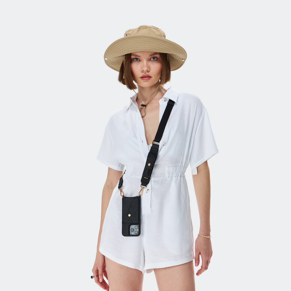 Model wearing the black Bandolier-style leather crossbody phone case, demonstrating its practicality with the adjustable strap comfortably slung over the shoulder