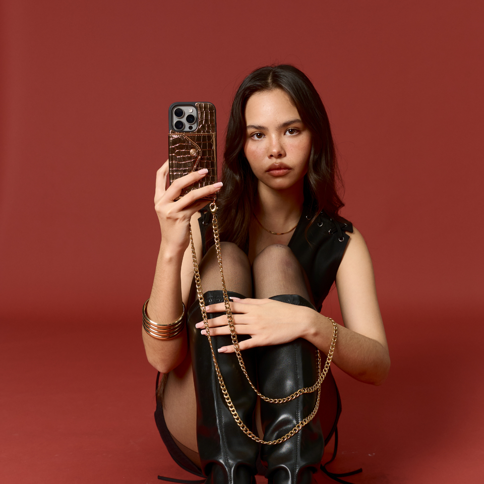 Model demonstrating the gold vegan Bandolier-style crossbody phone case, with the adjustable strap comfortably worn over the shoulder for hands-free functionality.